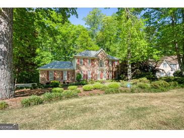 Traditional brick home featuring a lush landscaped front yard and surrounded by mature trees at 2402 Creekside Trce, Jonesboro, GA 30236