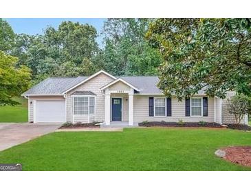 Charming one-story home with manicured lawn, attached garage, and mature trees providing shade at 3865 Lehigh Blvd, Decatur, GA 30034