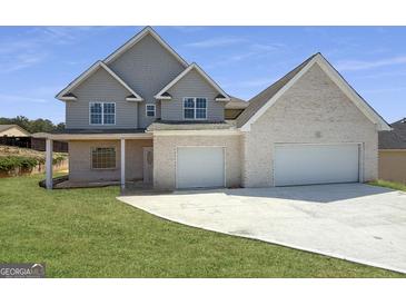 Charming two-story home featuring a two-car garage, a welcoming porch, and a neatly manicured lawn at 2873 Shoals Hill Ct, Dacula, GA 30019