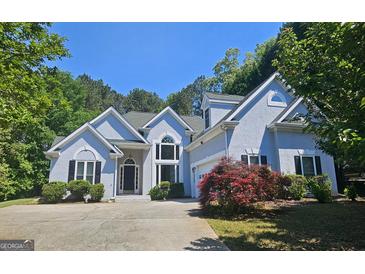 Beautiful two-story home featuring a well manicured lawn, mature trees and ample parking space in the driveway at 109 Windsong Dr, Stockbridge, GA 30281
