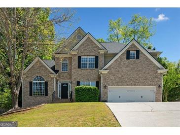 Charming two-story brick home with a well-manicured lawn and a two-car garage, set against a bright blue sky at 3338 Hackmatack Dr, Kennesaw, GA 30152