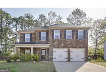 Charming two-story brick home featuring a two-car garage, inviting front porch, and manicured lawn at 1144 Bluecoat Cir, Hampton, GA 30228