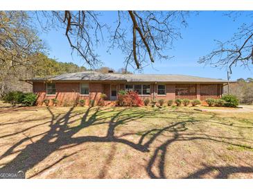 Charming brick ranch-style home with a well-maintained yard and mature landscaping under a clear blue sky at 461 Old Jackson Rd, Mcdonough, GA 30252