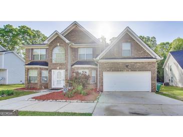 Charming two-story brick home with a manicured lawn and an attached two-car garage at 365 Othello Dr, Hampton, GA 30228