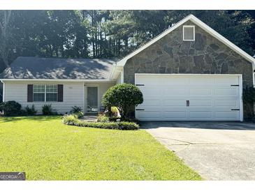 Charming single-story home featuring a stone facade and an attached two-car garage at 7665 Antebellum Ln, Riverdale, GA 30274