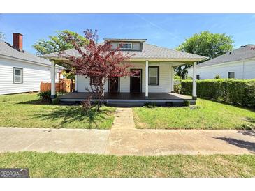 Charming single story home with a covered front porch and a small decorative tree in the front yard at 30 Poplar St, Porterdale, GA 30014