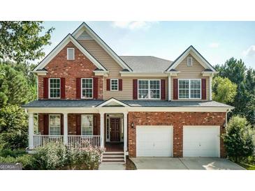 Charming two-story home featuring a brick and tan facade, a welcoming front porch, and a convenient two-car garage at 803 Baugh Springs Ln, Lawrenceville, GA 30044