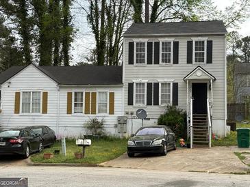 Two-story house with white siding, black shutters, a driveway and yard in need of some TLC at 3464 Kingswood Trl, Decatur, GA 30034