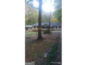 Single-story home featuring a screened porch and neutral siding nestled among mature trees at 40 Burma Rd, Mcdonough, GA 30252
