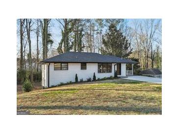 Charming single-story home with a white brick exterior and a well-manicured front yard at 1120 Starline Dr, Smyrna, GA 30080