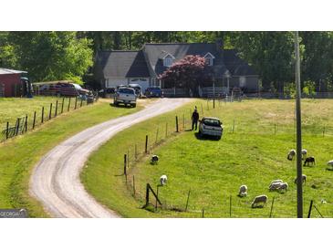 Picturesque home with a long gravel driveway and livestock grazing in the surrounding fields at 201 Little New York Rd, Carrollton, GA 30116