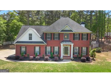 A charming two-story red brick home with landscaped yard and a lush green lawn at 65 Jacksons Vly, Sharpsburg, GA 30277