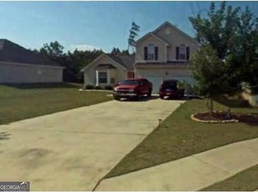 Two-story home boasts a well-manicured front lawn, a long driveway and attached two-car garage at 472 Harvick Cir, Stockbridge, GA 30281