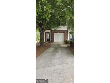 Brick townhome with a one car garage, mature trees, and a concrete driveway at 2867 Snapfinger Mnr, Decatur, GA 30035