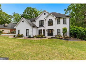 Charming two-story white home with black trim, lush lawn, and mature trees at 608 Bellenden Dr, Peachtree City, GA 30269