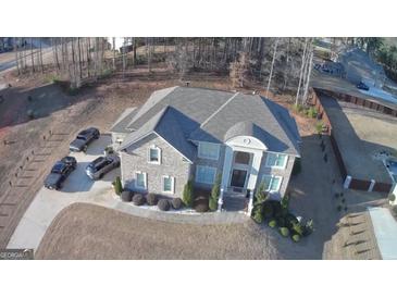 Stunning aerial view of a gray stone two-story home with a well-manicured lawn and ample parking at 116 Kalsum Trl, Ellenwood, GA 30294