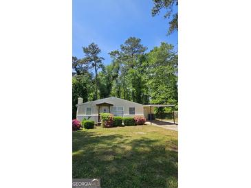 Charming home features a covered front porch, well-manicured lawn, mature trees, and convenient covered parking at 1973 Niskey Lake Sw Rd, Atlanta, GA 30331
