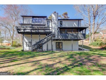 Expansive backyard view features a home with a multi-level deck, mature trees, and a lush lawn at 5284 Silver Creek Sw Dr, Lilburn, GA 30047