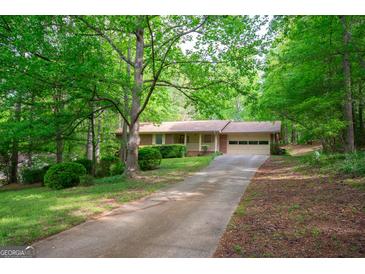Charming single-story home with brick accents, lush greenery, and a driveway leading to an attached garage at 215 Ridge Rd, Tyrone, GA 30290