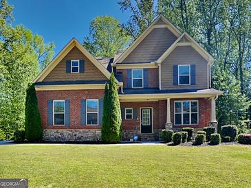 Charming two-story home with brick facade, manicured lawn, and mature trees at 143 Tara Blvd, Loganville, GA 30052
