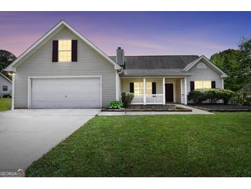 Charming one story home with a well manicured lawn and covered front porch at dusk at 146 Calico Loop, Grantville, GA 30220