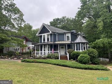 Charming two-story home with a welcoming porch, beautiful landscaping, and an American flag at 332 Wyngate Rd, Auburn, GA 30011
