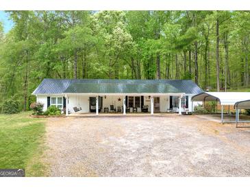 Charming single-story home featuring a metal roof, covered porch, and ample parking at 7616 Nicholson Rd, Cumming, GA 30028