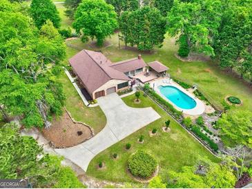 Stunning aerial view of a home featuring a pool, lush landscaping, and a long driveway at 171 Wynn Dr, Hampton, GA 30228