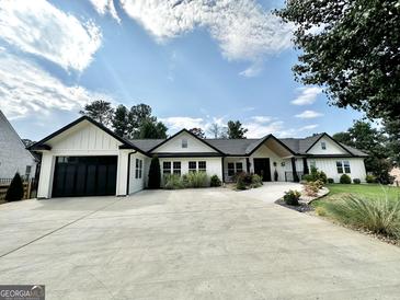 Beautiful white home with black trim, complemented by a well-manicured lawn and a spacious concrete driveway at 3550 N Bogan Rd, Buford, GA 30519