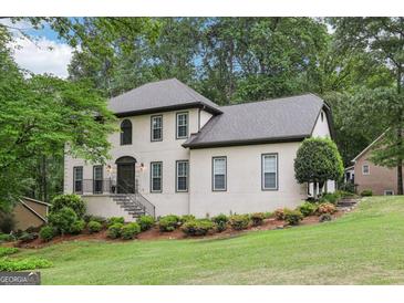 Charming two-story home with a landscaped yard and welcoming front entrance with gray roof and trim at 2819 Saddlebrook Nw Way, Marietta, GA 30064