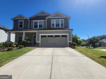 Two-story home with a gray exterior, well-manicured lawn, and a two-car garage on a clear, sunny day at 883 Ironhorse Sw Ln, Mableton, GA 30126