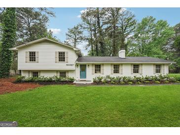 Charming, renovated home features white brick and siding, a bright blue door, and well-manicured landscaping at 4327 Welligton Hill Ln, Snellville, GA 30039