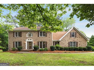 Charming two-story brick home with lush green lawn, mature trees, and well-maintained landscaping at 100 Hartford Pl, Fayetteville, GA 30214