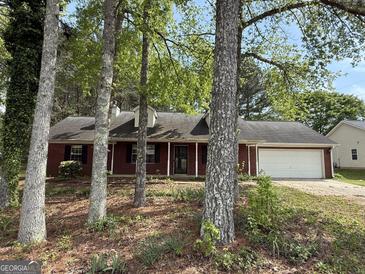 Charming brick ranch home with a two-car garage and a well-manicured front yard shaded by mature trees at 130 Elm St, Hampton, GA 30228