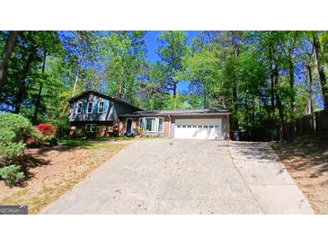 Charming home featuring a brick and siding exterior, complemented by a two-car garage and lush surrounding trees at 644 Garden Grove Dr, Lawrenceville, GA 30044