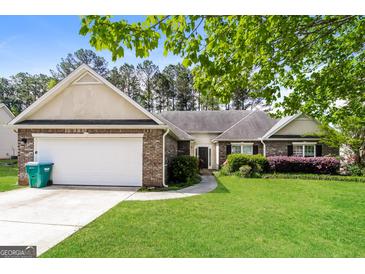 Charming single-story home with brick facade, attached garage, and well-maintained lawn at 121 Crestwood Ct, Hampton, GA 30228