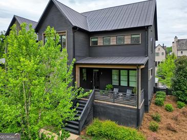 Beautiful modern home with black siding, metal roof, a deck, and professional landscaping at 300 Mado Ln # 329, Chattahoochee Hills, GA 30268
