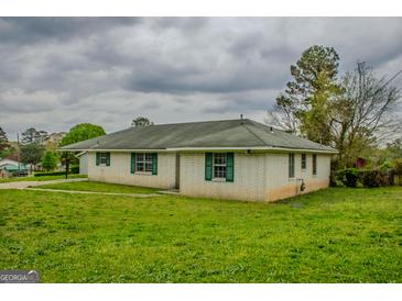 Ranch-style home with a white brick exterior, green shutters, and a well-maintained lawn at 7017 Sun Valley Way, Riverdale, GA 30274