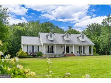 Charming white farmhouse with a metal roof, dormers, and expansive green lawn at 333 Old Carrollton Rd, Roopville, GA 30170