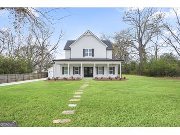 Beautiful two-story farmhouse-style home featuring a welcoming front porch and lush green lawn at 61 Main St, Moreland, GA 30259