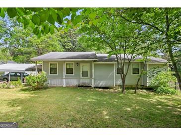 Charming single-story home with light gray siding, a covered front porch, and a well-maintained lawn with mature shade trees at 3580 Dorris Cir, Douglasville, GA 30135
