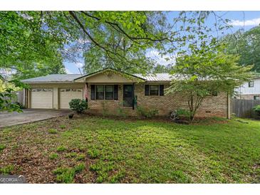 Charming brick home with a well-manicured front yard, mature trees, and a two-car garage at 235 Castlegate Cir, Carrollton, GA 30116
