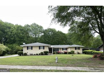 Charming ranch-style home featuring a well-manicured lawn, flowering shrubs, and brick facade at 8672 Bowden St, Douglasville, GA 30134