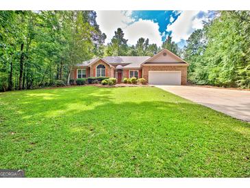 Charming single-story brick home featuring an attached garage, a well-manicured lawn and mature trees at 250 Kari Glen Dr, Fayetteville, GA 30215