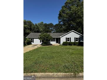 Charming one-story home with light-blue siding and a well-manicured lawn at 2204 Liberty Sw Ln, Conyers, GA 30094