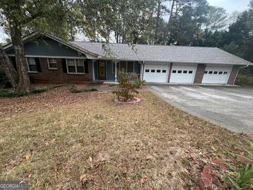 Charming one-story home with a brick facade and an attached three-car garage at 1329 Springwood Nw Dr, Conyers, GA 30012