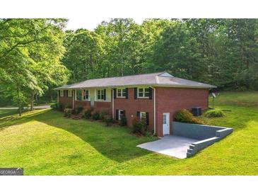 Brick home with a lush, green lawn and mature trees, plus a convenient drive-under garage at 292 S Prospect Ave, Waco, GA 30182