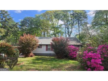 Charming home with beautiful landscaping, colorful azaleas, and mature trees, offering great curb appeal at 402 Emmett St, Riverdale, GA 30274