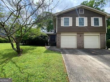 Charming two-story home features a lush front yard, a two-car garage, and classic architectural details at 4457 Huntshire Dr, Stone Mountain, GA 30083
