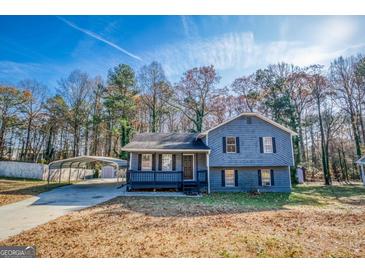 Two-story home featuring a carport, a welcoming front porch, and tasteful landscaping at 1355 Compton Woods Dr, Loganville, GA 30052